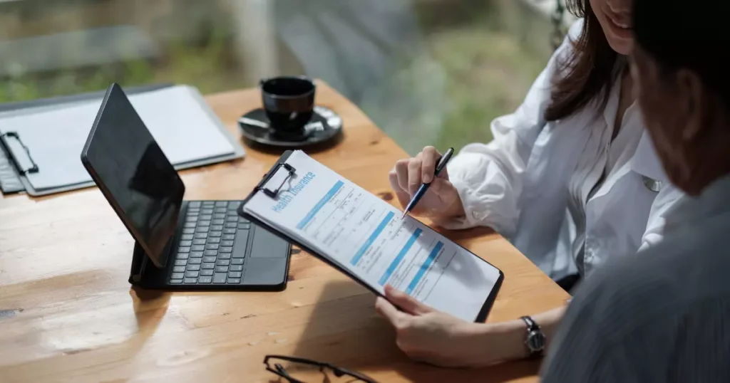 A person holding a pen and writing on a clipboard