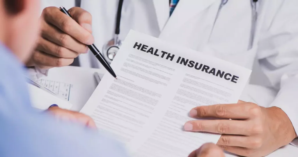 A person holding a health insurance policy and a pen