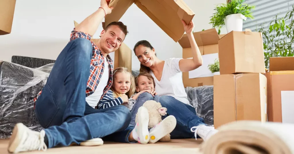 A family sitting on the floor in a cardboard house