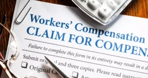 Close up of a workers compensation insurance claim form with glasses and a pen